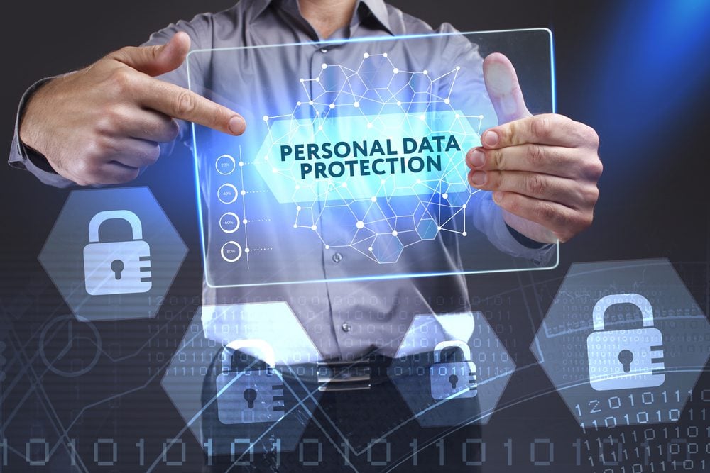 Man holding holographic tablet labeled "personal data protection" and lock icons against a backdrop of data