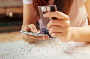 Woman holding mobile phone in one hand and credit card in the other