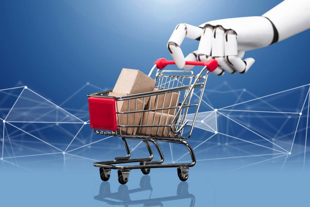 eCommerce_Robotic Hand Holding Miniature Shopping Cart Filled With Many Cargo Boxes Against Blue Technology Background