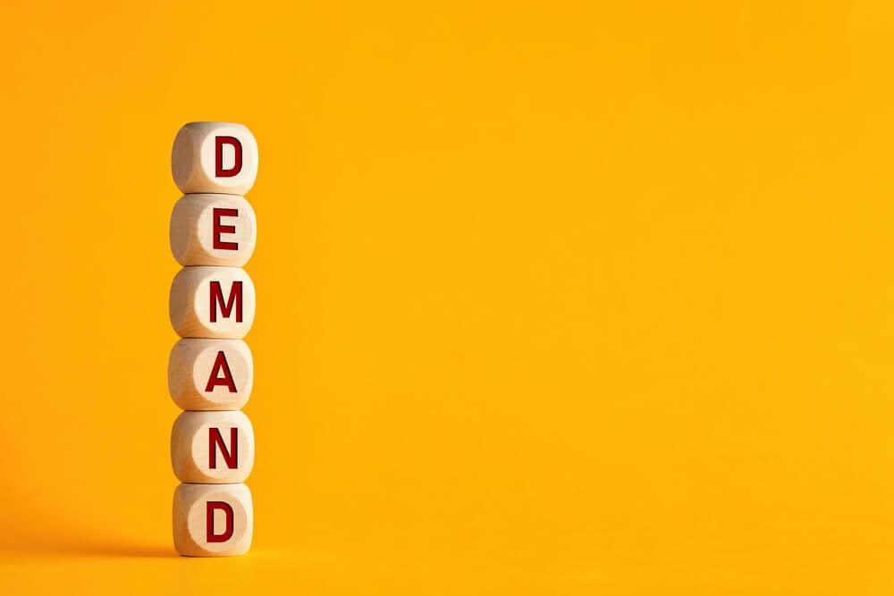 demand_The word demand on stacked wooden cubes. Demand increase or rise in economy or business concept.