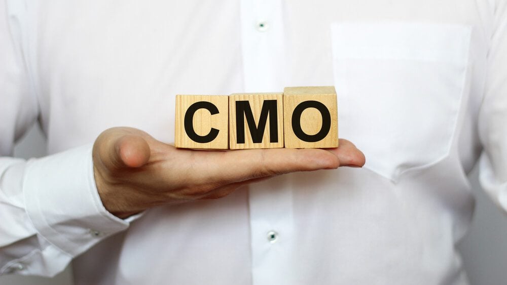 CMO_A businessman holds wooden cubes with a word CMO on a white background, with space to copy the text, business concept