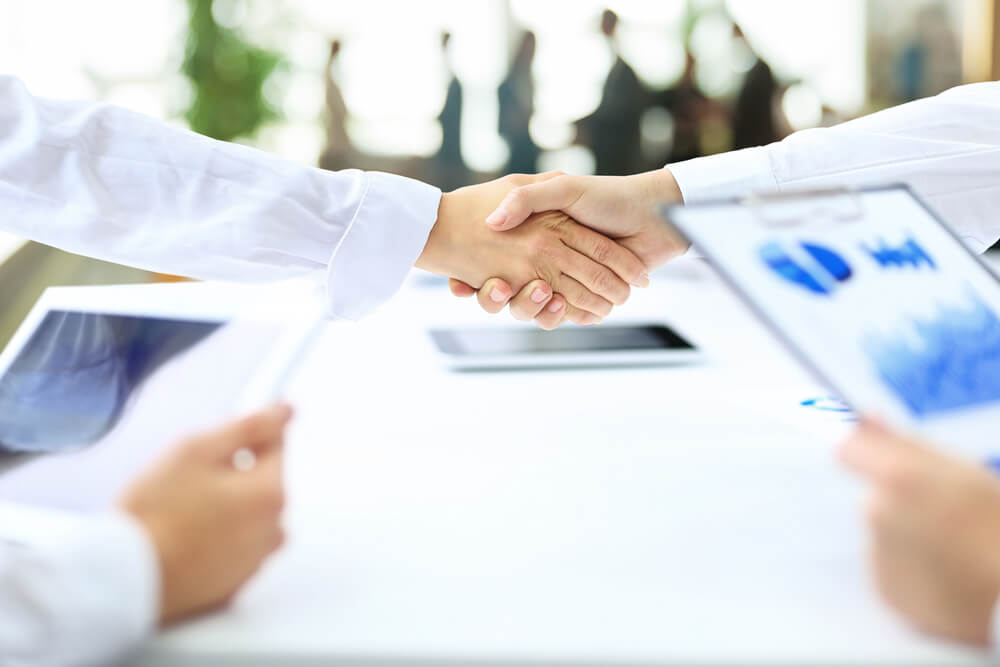 demand_handshake business partners after the conclusion of successful contract on the background of the workplace