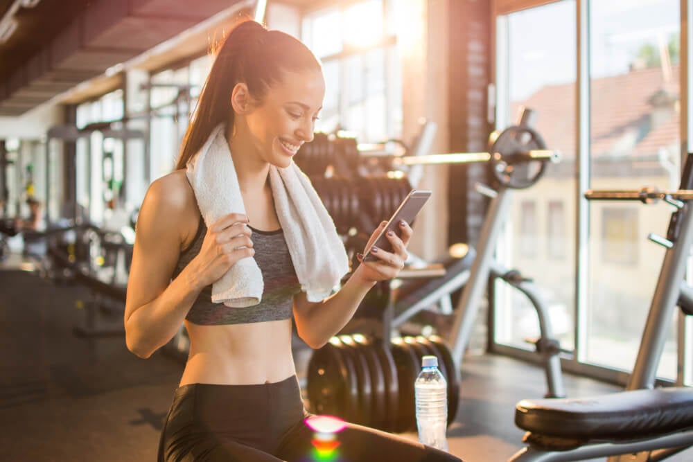 chatGPT_Young fit woman using smart phone at gym