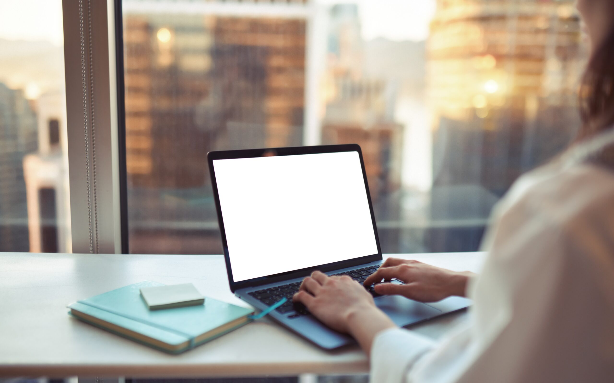 A businesswoman looks up New York FCMO marketing strategies on a laptop with the city skyline beyond the office