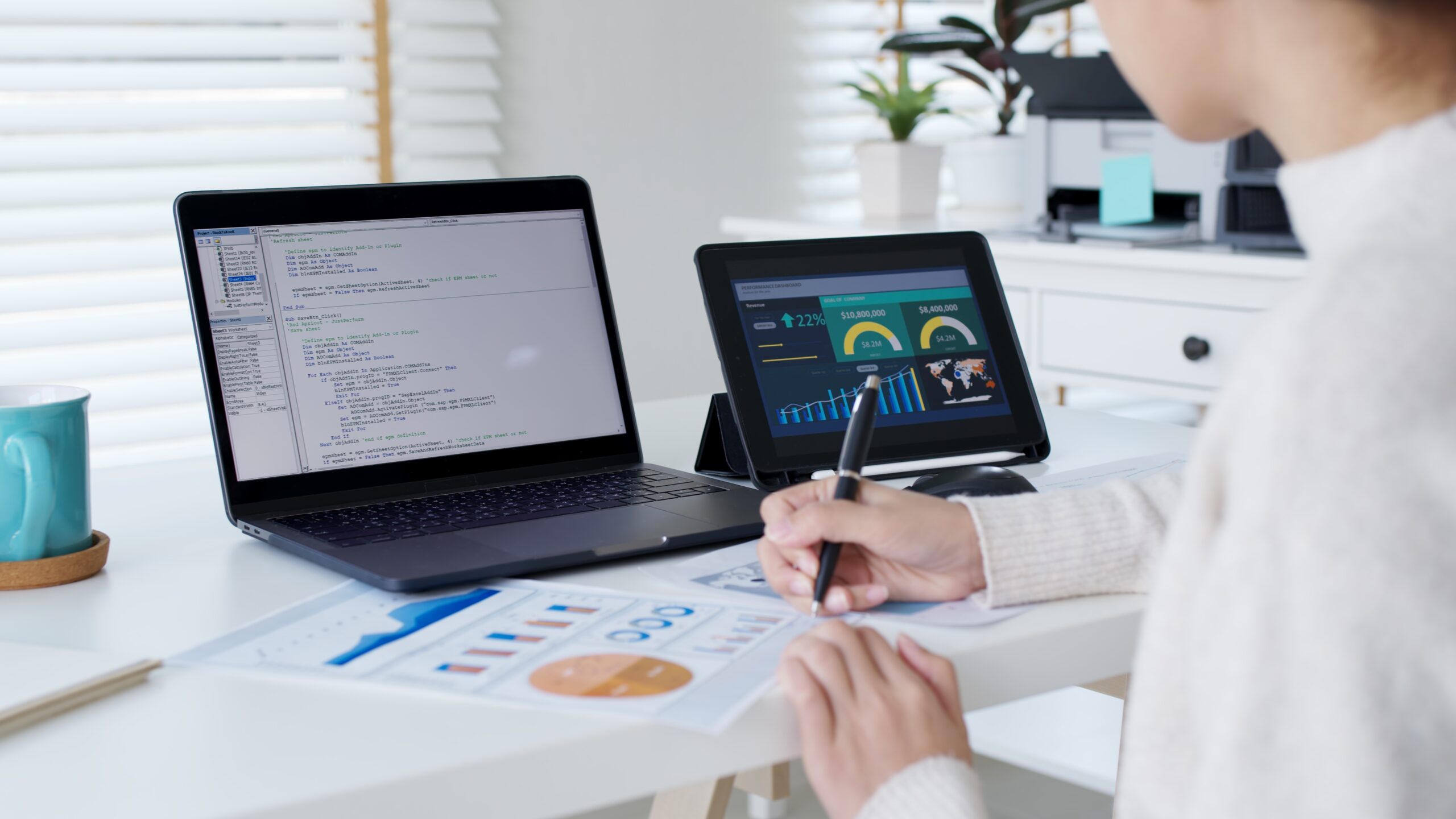 A businesswoman sits at a desk with a computer, paper charts, and a pen working on marketing strategies for Atlanta startups