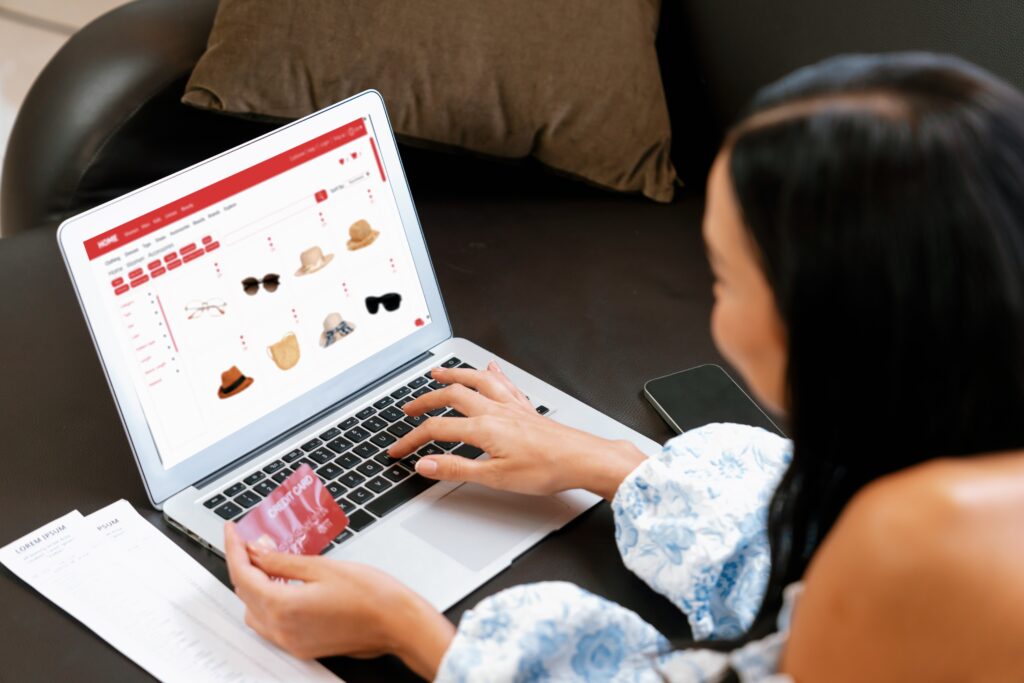 A woman holds a red credit card as she retail shops online with her laptop in Chicago 