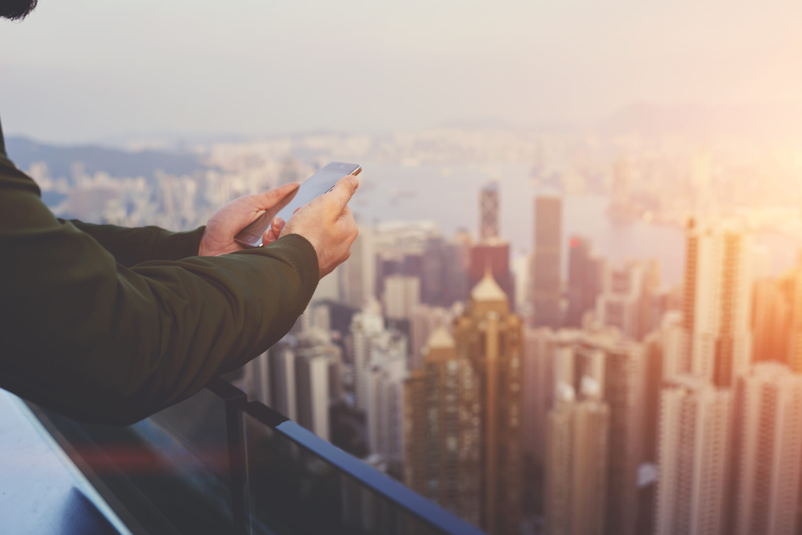 A close-up of hands holding a phone with the NYC skyline in the background; he's working on e-commerce marketing with a NY FCMO