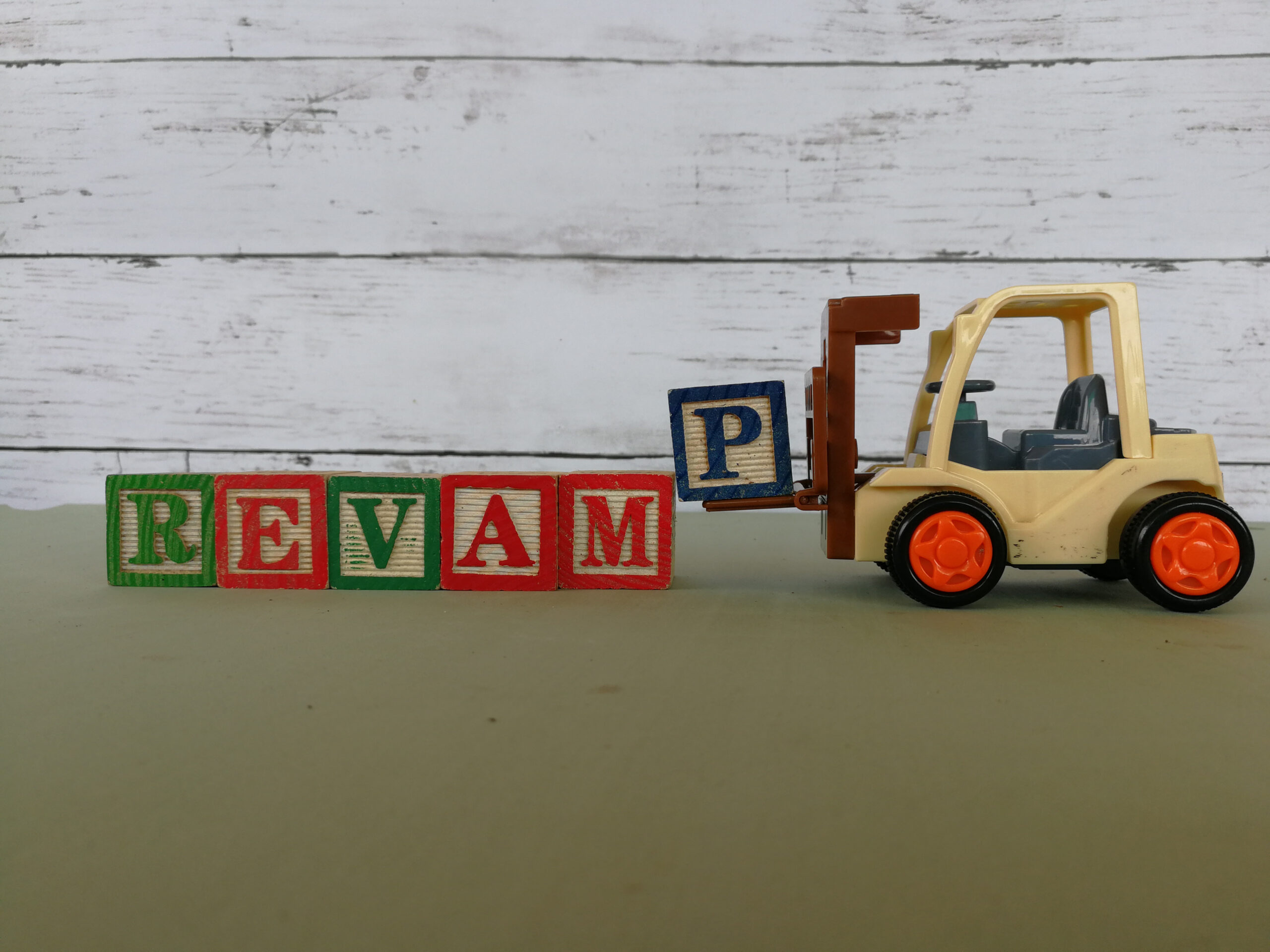 A beige forklift moves wooden blocks spelling “revamp” in Chicago, representing a fractional cmo consultant’s work