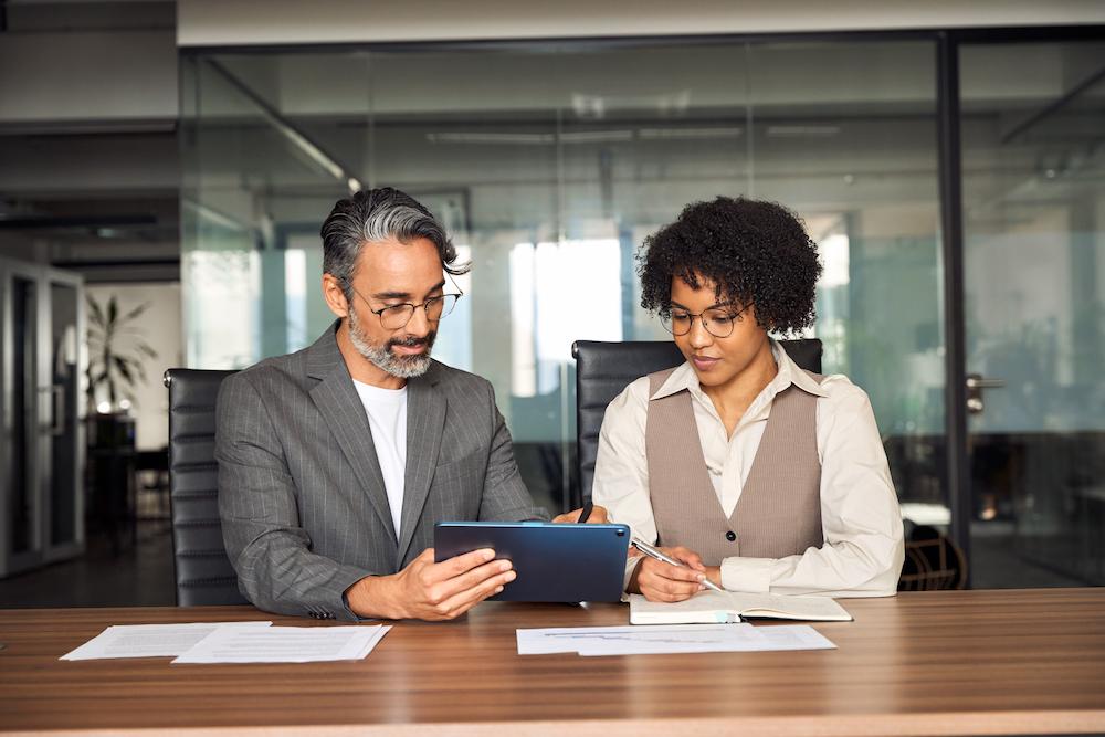 Two Atlanta Content Marketing Agency Services team members sit at a desk with a tablet and paper