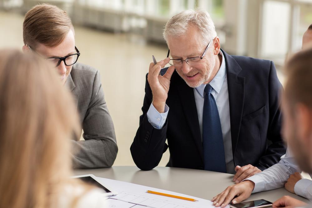 An Intermin CMO in a suit reviews the marketing strategy with the professional-looking marketing team