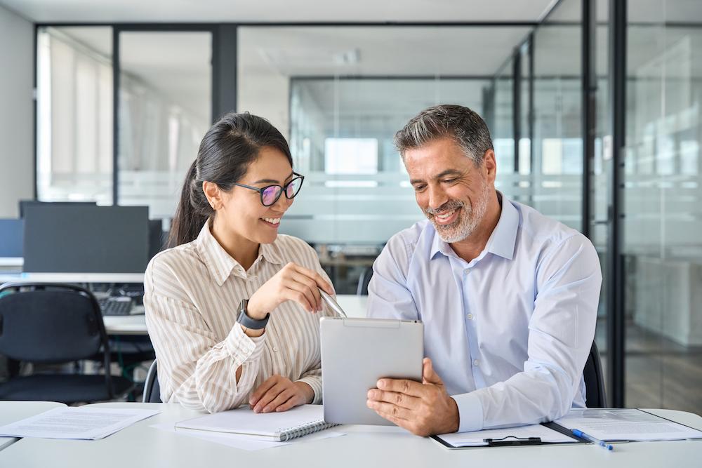 Two marketing strategy consultants sitting at a white desk in an office review a new campaign