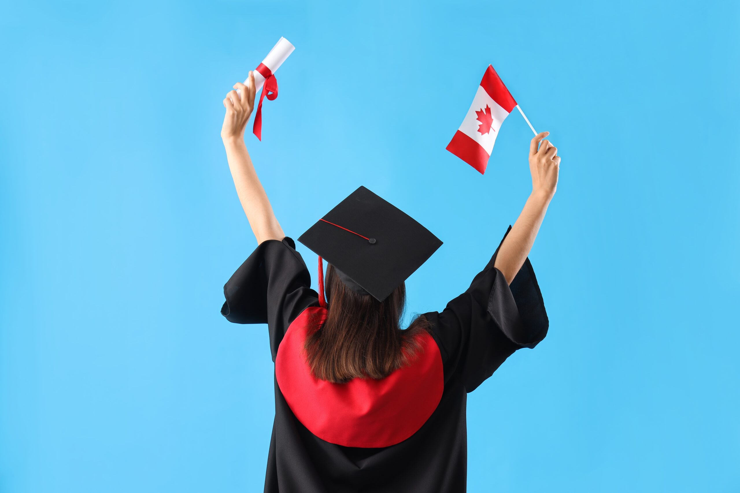 A female graduate student holds up a Canadian flag and diploma