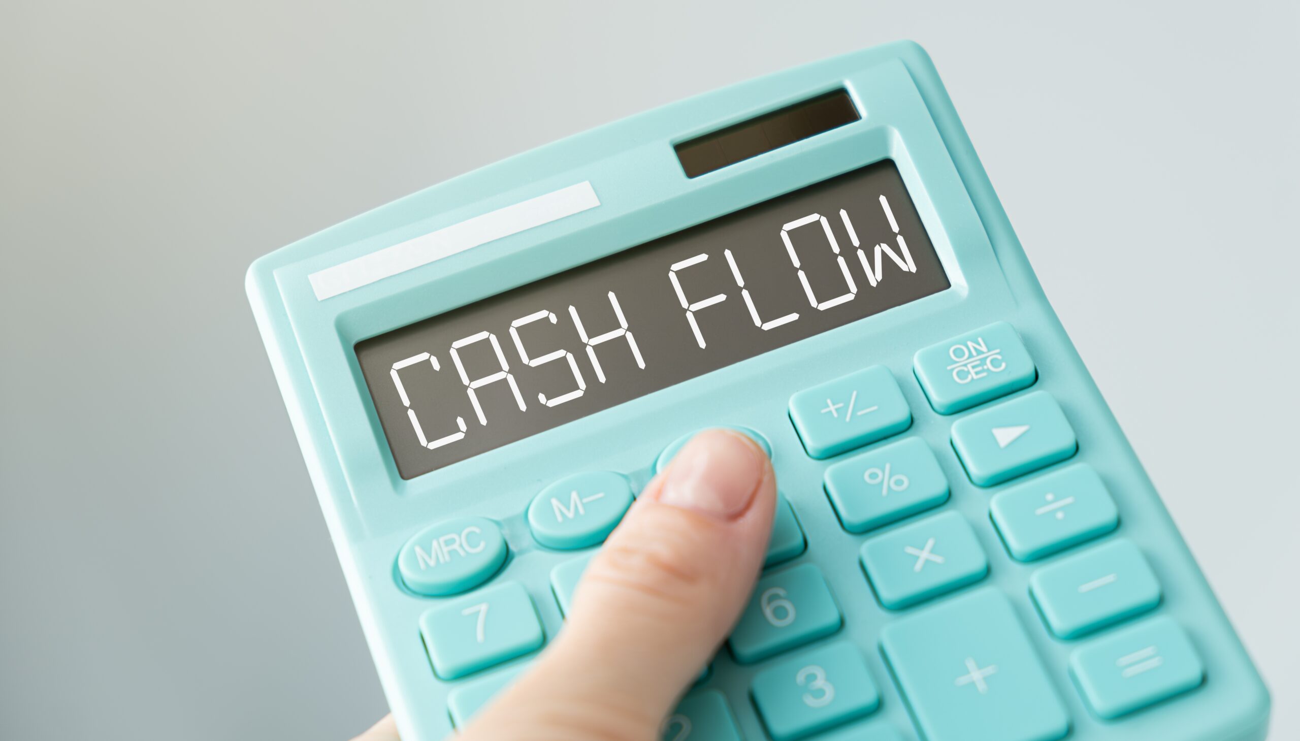 finger points to words on teal calculator CASH FLOW